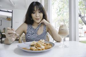 drôle de jeune femme asiatique mangeant des pâtes savoureuses au café photo