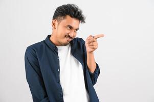 portrait d'un jeune homme asiatique souriant en chemise bleue pointant le doigt à côté isolé sur fond blanc photo