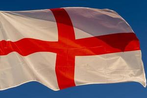 agitant le drapeau anglais croix rouge sur blanc isolé sur bleu photo