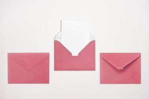 trois enveloppes roses sur fond blanc dont une ouverte avec une note à l'intérieur. place pour votre texte. service de livraison.