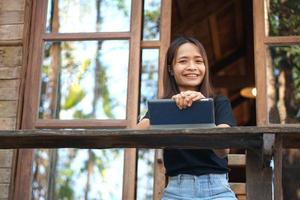 les femmes asiatiques sont heureuses de s'asseoir et de travailler dans un café. il y a des arbres verts entourés par la nature. la planification d'entreprise est une bonne idée. photo