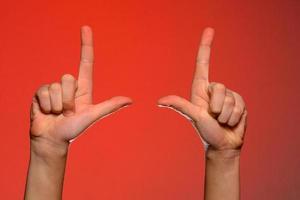 main humaine aux doigts pliés, montre un index qui symbolise un pistolet, isolé sur fond rouge photo