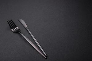 couteau et fourchette de cuisine en métal sur fond de béton texturé foncé photo