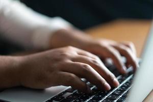 mains tapant sur un ordinateur portable. homme d'affaires travaillant au bureau photo