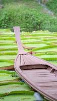 gros plan sur un bateau vintage en bois dans l'étang de feuilles de lotus sur le terrain de la porte. photo