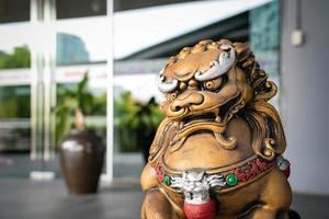 La statue de lion du dieu doré chinois est l'empereur d'ornement de la structure zen d'asie devant la porte pour protéger la mauvaise chose qui entre. photo