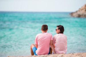 couple de vacances heureux se reposant sur le sable blanc et l'eau turquoise immaculée sur la plage en grèce. photo