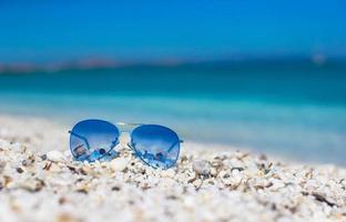 gros plan de lunettes de soleil bleues colorées sur la plage tropicale. photo