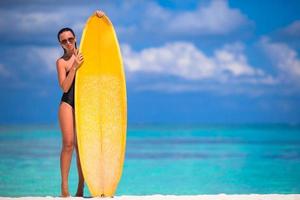 heureuse jeune femme de surf à la plage avec une planche de surf photo