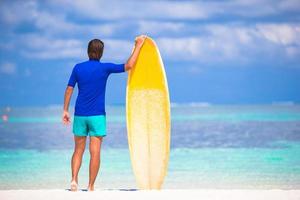 heureux jeune homme surfant sur la côte tropicale photo