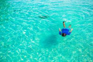 jeune homme plongée en apnée dans des eaux turquoises tropicales claires photo