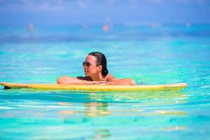 jeune surfeuse surfant dans une mer turquoise photo