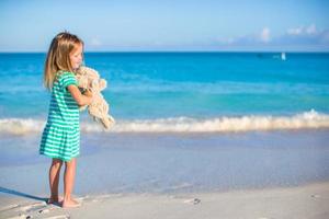 adorable petite fille avec son jouet lapin en vacances à la plage tropicale photo