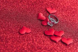 veux-tu m'épouser. bague de mariage et de nombreux coeurs rouges sur fond de paillettes rouges. concept de mariage de proposition de mariage de fiançailles. st. carte postale de la saint valentin. bannière le jour de la saint valentin. photo