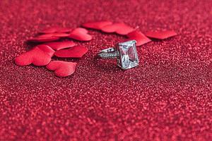 veux-tu m'épouser. bague de mariage et de nombreux coeurs rouges sur fond de paillettes rouges. concept de mariage de proposition de mariage de fiançailles. st. carte postale de la saint valentin. bannière le jour de la saint valentin. photo