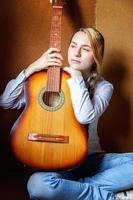 jeune femme hipster assise sur le sol et jouant de la guitare à la maison. adolescente apprenant à jouer de la chanson et à écrire de la musique dans sa chambre. passe-temps, mode de vie, détente, instrument, loisirs, concept d'éducation. photo