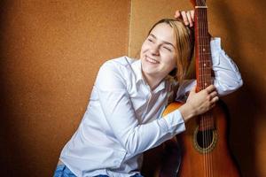 jeune femme hipster assise sur le sol et jouant de la guitare à la maison. adolescente apprenant à jouer de la chanson et à écrire de la musique dans sa chambre. passe-temps, mode de vie, détente, instrument, loisirs, concept d'éducation. photo