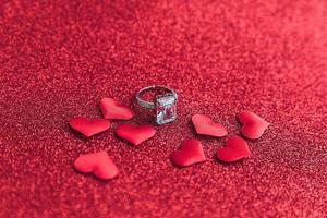 veux-tu m'épouser. bague de mariage et de nombreux coeurs rouges sur fond de paillettes rouges. concept de mariage de proposition de mariage de fiançailles. st. carte postale de la saint valentin. bannière le jour de la saint valentin. photo