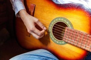 mains de femme jeune hipster jouant de la guitare à la maison. adolescente apprenant à jouer de la chanson et à écrire de la musique dans sa chambre. passe-temps, mode de vie, détente, instrument, loisirs, concept d'éducation. photo