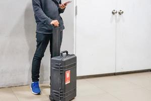 Jeune homme asiatique à l'aide de smartphones avec ses bagages à la vérification des vols dans les aéroports, voyage à l'étranger concept photo