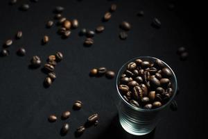 grains de café dans un verre sur fond noir photo