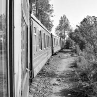 petit train se déplaçant sur le versant de la montagne, belle vue, un côté montagne, un côté vallée se déplaçant sur le chemin de fer jusqu'à la colline, parmi la forêt naturelle verdoyante. petit train de kalka à shimla en inde photo