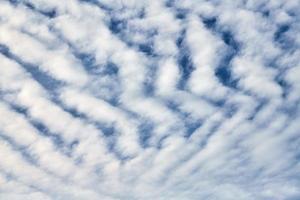 beau ciel bleu avec des nuages blancs inhabituels d'altocumulus undulatus, une formation de nuages extraordinaire photo