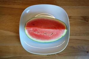 couper la pastèque sur une assiette, table en bois - vue de dessus photo