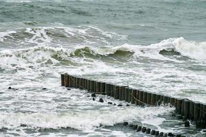 vue sur la mer bleue avec des vagues écumantes et des brise-lames en bois photo