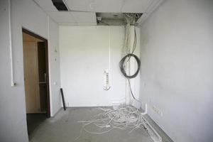 dans un bureau vide, de nombreux fils électriques pendent du plafond. photo
