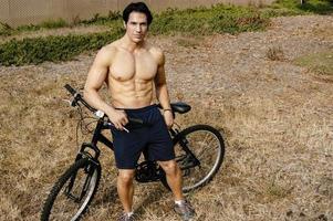 athlète masculin pose avec son vélo et exhibe son corps chaud. photo