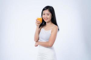 belle femme asiatique buvant du jus d'orange, des concepts de soins de santé, de peau, de beauté et de bien-être, isolée sur fond blanc photo