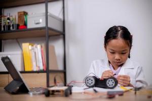 les étudiants asiatiques apprennent à la maison en codant des voitures robotisées et des câbles de carte électronique dans la tige, la vapeur, le code informatique de la technologie des sciences de l'ingénierie mathématique dans la robotique pour les concepts des enfants. photo