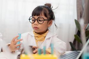 petite fille asiatique mesurant la température de l'eau chaude et froide pour un cours en ligne expérimental scientifique facile photo