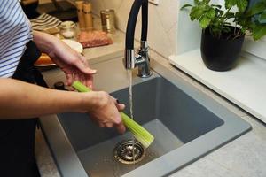 femme laver le céleri frais dans la cuisine photo