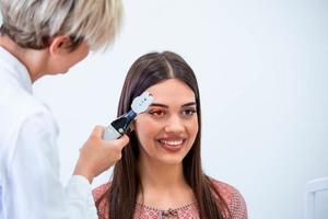 vérification de la santé oculaire avec équipement ophtalmologique en laboratoire. à l'aide d'un oculiste d'appareil spécial essayant d'améliorer la vision d'une jeune jolie fille. travailler avec des dispositifs médicaux pour la santé oculaire. photo