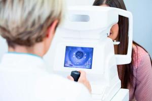 une femme médecin ophtalmologiste vérifie la vision oculaire d'une jeune femme séduisante dans une clinique moderne. médecin et patient en clinique d'ophtalmologie. photo