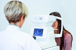 une femme médecin ophtalmologiste vérifie la vision oculaire d'une jeune femme séduisante dans une clinique moderne. médecin et patient en clinique d'ophtalmologie. photo