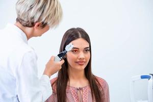 vérification de la santé oculaire avec équipement ophtalmologique en laboratoire. à l'aide d'un oculiste d'appareil spécial essayant d'améliorer la vision d'une jeune jolie fille. travailler avec des dispositifs médicaux pour la santé oculaire. photo