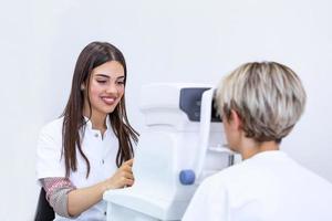 une femme médecin ophtalmologiste vérifie la vision oculaire d'une jeune femme séduisante dans une clinique moderne. médecin et patient en clinique d'ophtalmologie. photo