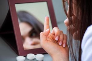 jeune femme mettant une lentille de contact dans son œil droit, gros plan photo