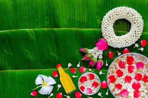fond de festival de songkran avec guirlande de jasmin, fleurs dans des bols d'eau et eau parfumée pour la bénédiction sur fond de feuille de bananier humide. photo