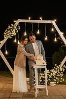 les jeunes mariés coupent et goûtent joyeusement le gâteau de mariage photo