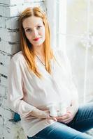 fille enceinte rousse dans un chemisier léger et un jean bleu photo