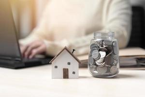 une femme qui travaille économise de l'argent pour une nouvelle maison. concept d'économiser de l'argent pour un nouveau bâtiment résidentiel. travaillez dur, économisez plus pour un nouveau lieu de vie. photo