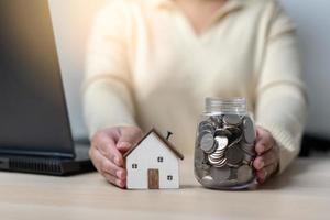 une femme qui travaille économise de l'argent pour une nouvelle maison. concept d'économiser de l'argent pour un nouveau bâtiment résidentiel. travaillez dur, économisez plus pour un nouveau lieu de vie. photo