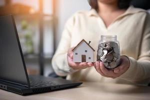 une femme qui travaille économise de l'argent pour une nouvelle maison. concept d'économiser de l'argent pour un nouveau bâtiment résidentiel. travaillez dur, économisez plus pour un nouveau lieu de vie. photo