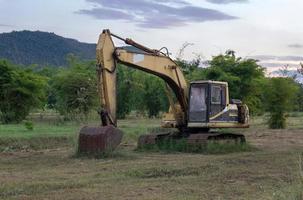 vieille pelleteuse sur chantier dans les champs verts avec coucher de soleil photo