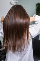 une chevelure brune droite et saine qui a subi la procédure de lissage des cheveux. cheveux bruns lisses, brillants et sains photo