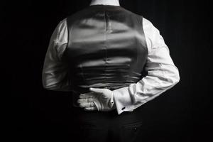 portrait de majordome ou serveur en gilet et gants blancs debout à l'attention élégante. l'industrie des services et la courtoisie professionnelle. photo
